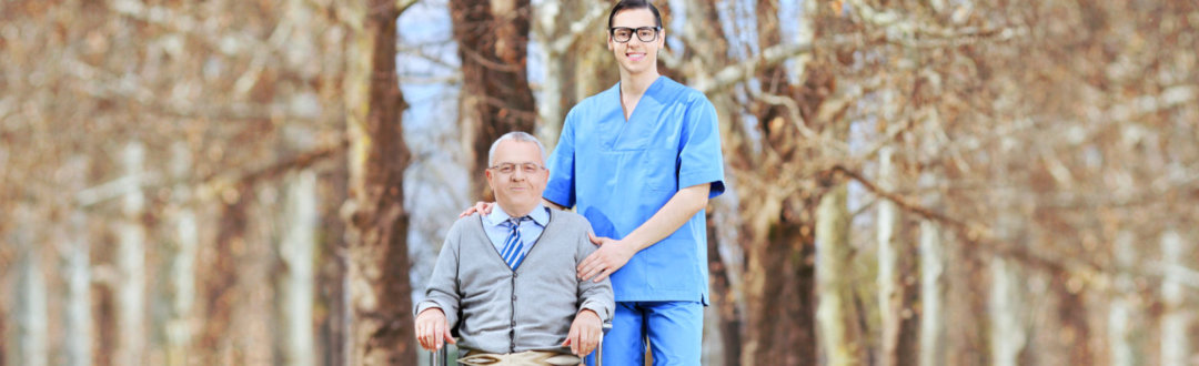 caregiver and senior man sitting in the wheel chair smiling